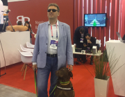Na zdjęciu znajdują się mężczyzna – Piotr Witek z firmy Utilitia wraz ze swoim psem przewodnikiem, w tle widać stoisko NCBiR na Europejskim Kongresie Gospodarczym